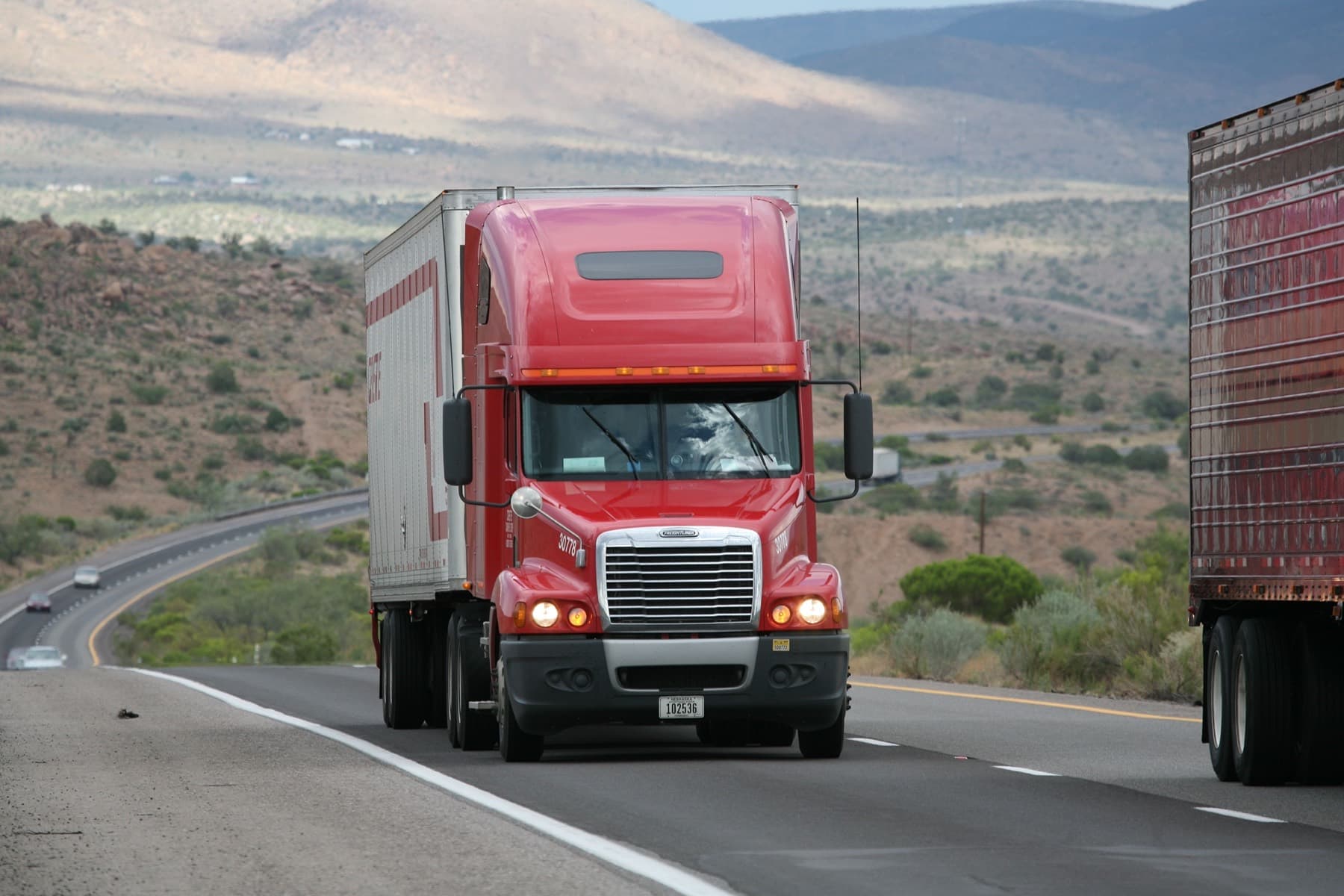 Red semi tractor pulling a trailer along an interstate